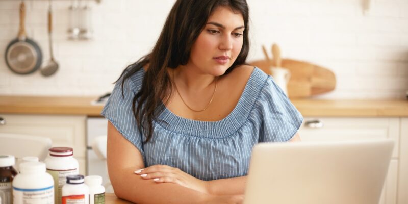 mujer sentada en la cocina usando una computadora portátil