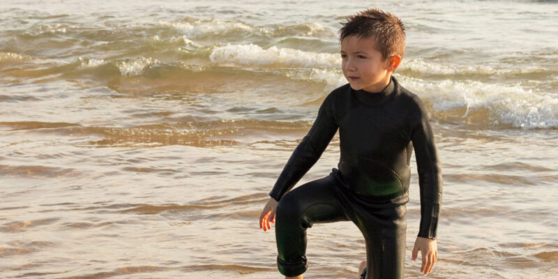 niño surfeando en la playa