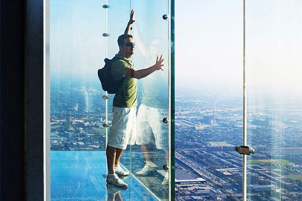 Hombre apoyado contra una ventana de vidrio en un edificio alto