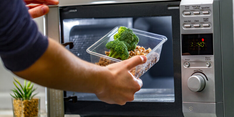 person putting food into microwave