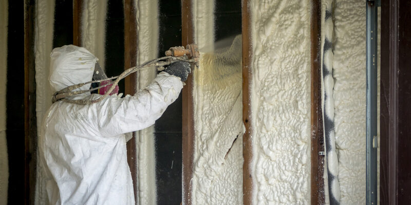 person spraying insulation foam into wall