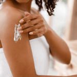 Black woman applying moisturizing lotion