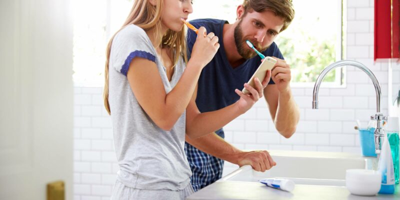 man and woman brushing their teeth