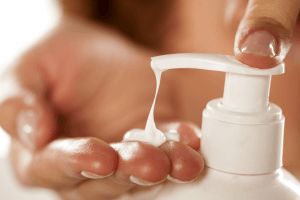 Young brown woman applying moisturizer to face.