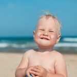 bebé con protector solar en la playa