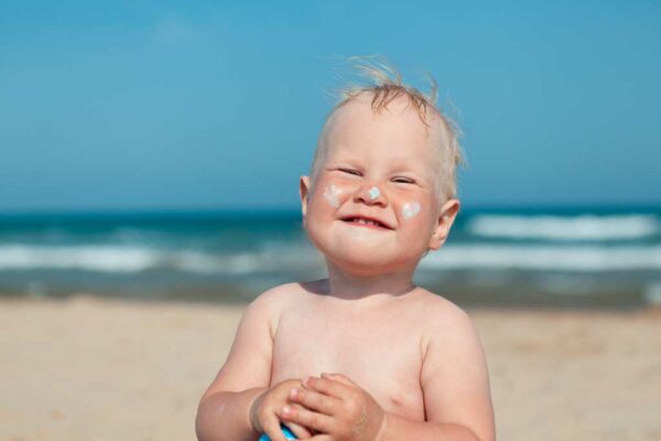 bebé con protector solar en la playa